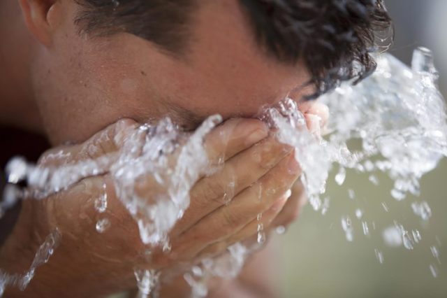 man splashing face with water